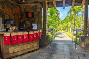 The elegant entrance of Rhumerie de Chamarel surrounded by lush green fields.