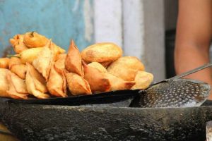 A plate of crispy samosas with dipping sauce.