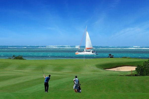 Golfer on the Anahita Golf Course at Four Seasons Resort Mauritius, with ocean views in the background.
