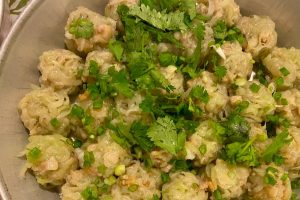 A bowl of Mauritian boulettes served in broth with herbs.